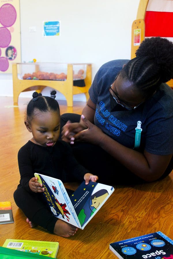 A mom and her infant daughter read a book together at Impression 5 Science Center, one of the best places in Michigan to visit with kids.