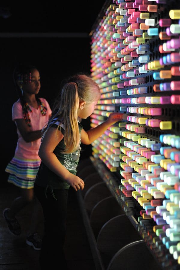 Two young girls explore a spectrum light exhibit at Impression 5 Science Center.