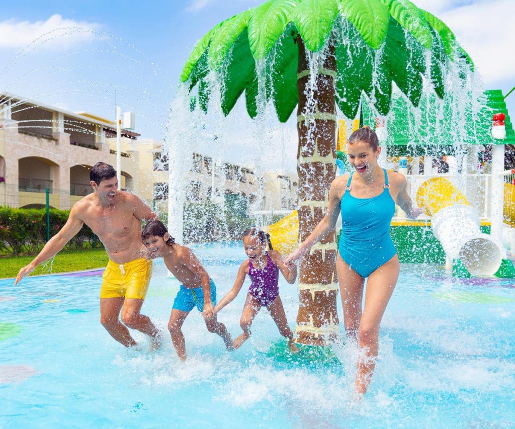 A family of four splashes together at a splash pad at Moon Palace The Grand - Cancun, one of the best hotels in Mexico with large rooms for families.