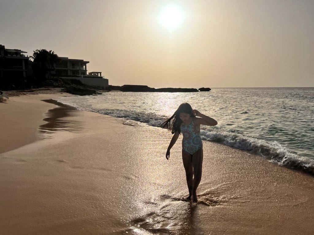 A young girl walks along the beach at sunset in Anguilla, one of the best places to visit during Easter with your family.