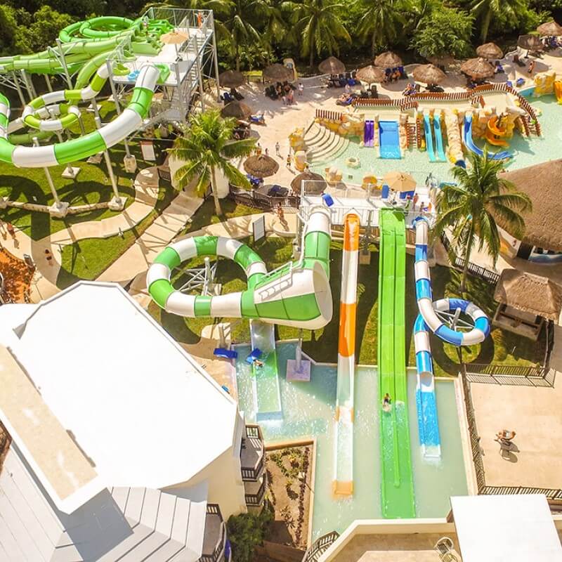 An aerial view of the large water park at Sandos Caracol Eco Resort, featuring huge water slides and bright colors.