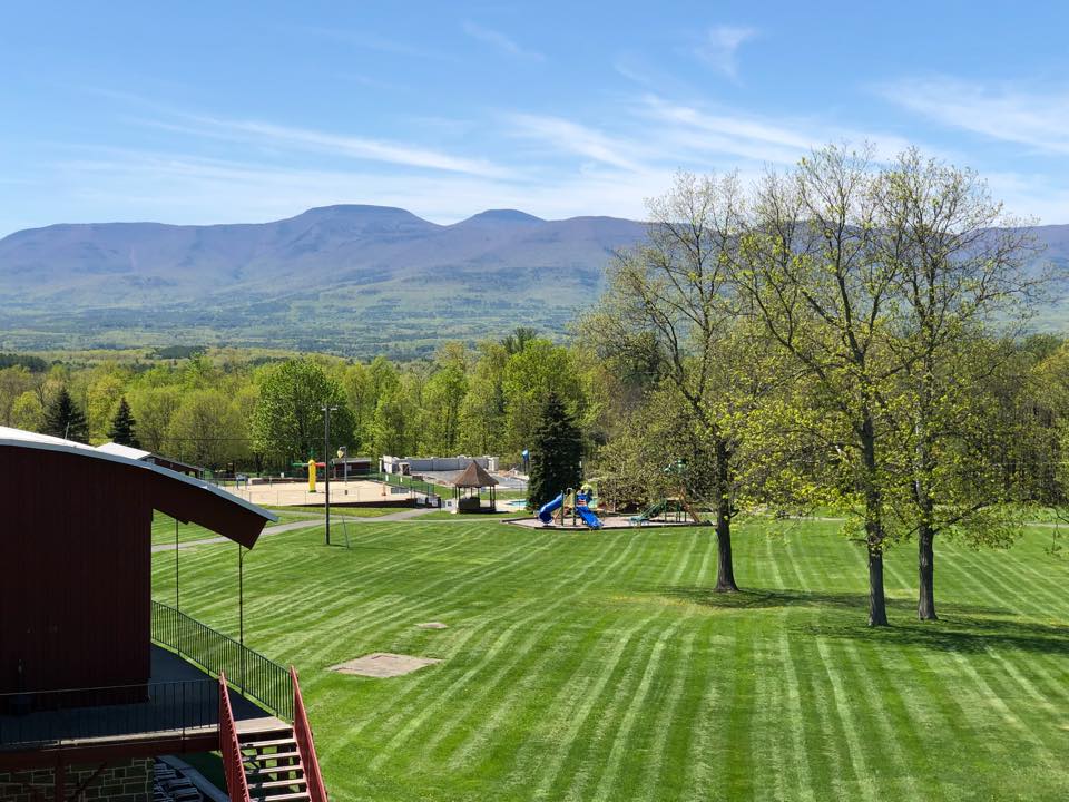 A cabin, along a lush green lawn dotted with trees at Sunny Hill Resort and Golf Course, one of the best all-inclusive hotels in the United States for families.