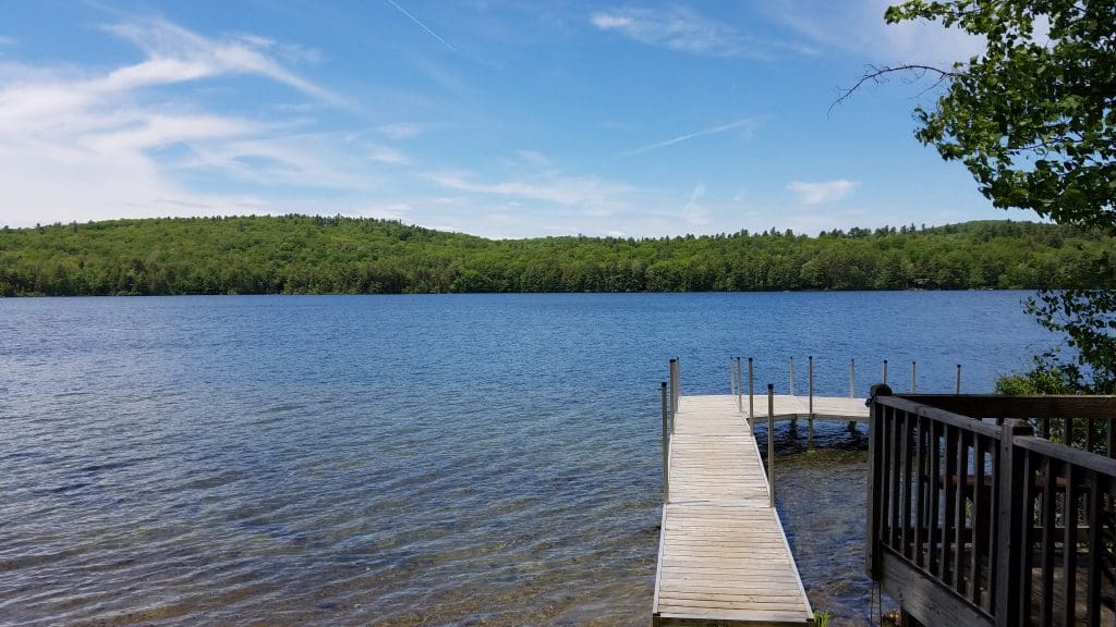 An empty dock leads into the lake off-shore from The Inn at East Hill Farm on a sunny day.