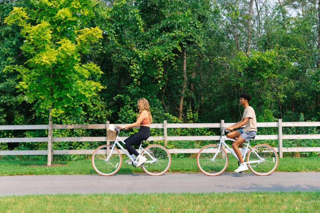 Two adults bike along a path at The Lake House On Canandaigua during the summer.