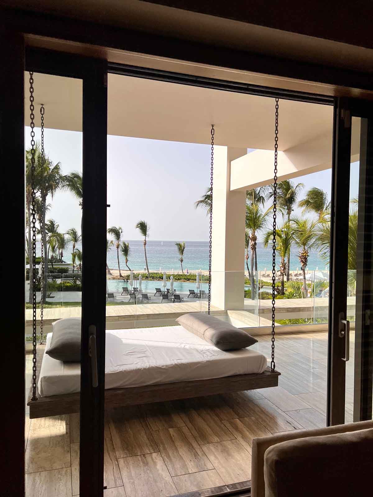 A swing day bed on the porch of a two-bedroom suite at Four Seasons Resort and Residences Anguilla overlooking an ocean view.