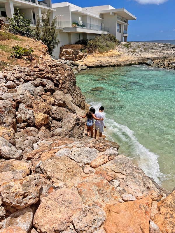 Two kids wander down a rock beach in Anguilla.