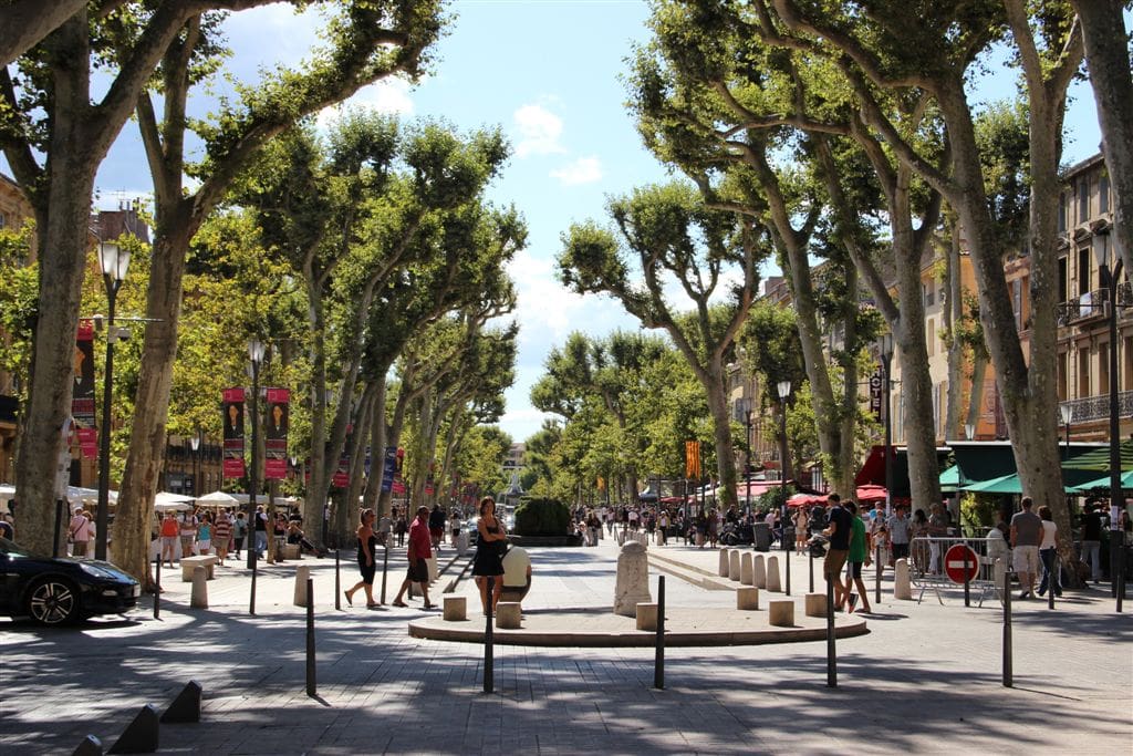 A view of a street in Aix en Provence, with people wandering about on a nice summer day.