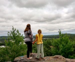 A mom and her daughter stand atop Mt. Simon, the highest point in Eau Claire, looking out toward the scenic view of the Chippewa Valley below.