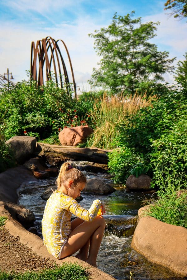 A young girl plays in the water of a splash stream in River Prairie Park, one of the best things to do in Eau Claire with kids.