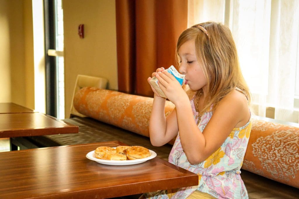 A young girl eats a hotel buffet breakfast, while staying at the Staybridge Suites Eau Claire - Altoona.