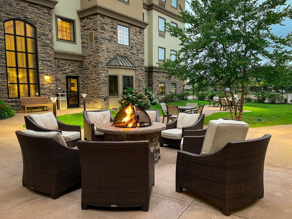 A lovely fire pit surrounded by six chairs in a hotel courtyard.