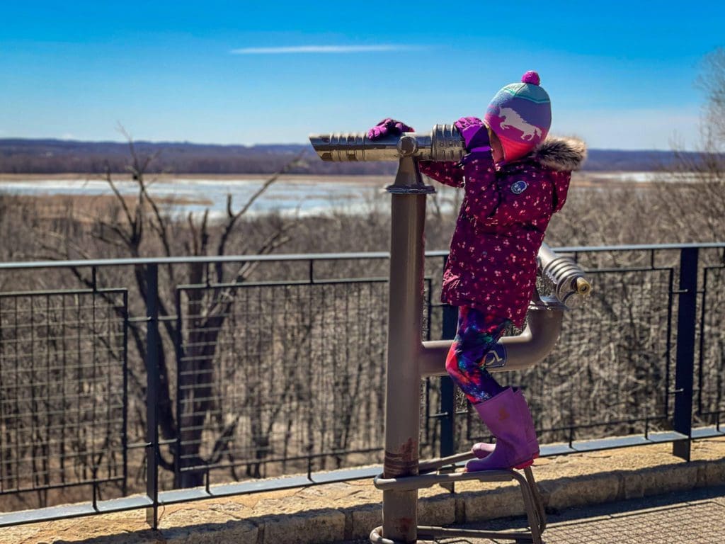 A young girl looks through a view finder at the Minnesota Valley National Wildlife Refuge in Bloomington, one of the best places to explore in the Twin Cities with kids.