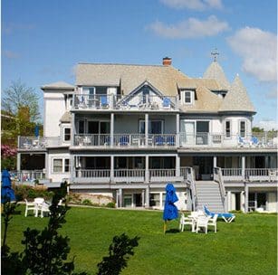 The exterior of the main building at Beachmere Inn in Ogunquit, Maine, featuring a lush lawn and guest room balconies along the exterior of the building.