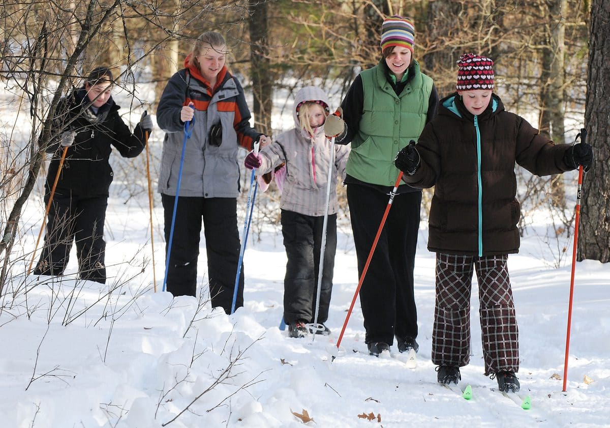 A family of five cross-country skis along a groomed winter trail in Beaver Creek Reserve.