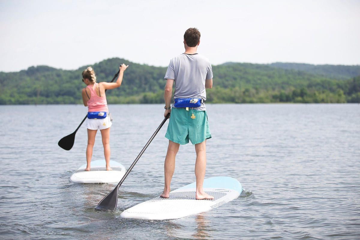 A man and a woman, each on their own paddle board, explore the lake at Blackberry Farm.