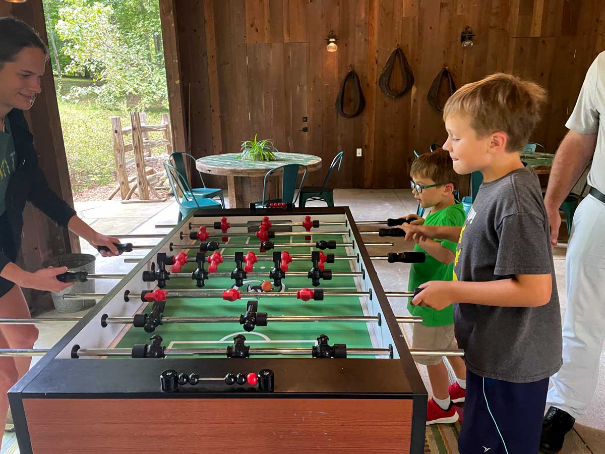 A mom and her two young sons play foosball in the game room, during a family getaway to Blackberry Farm in Tennessee.