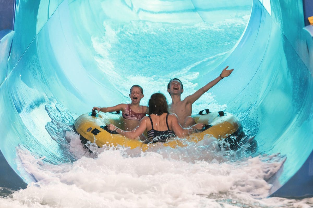 Three kids shoot down a waterslide on a tube at Great Wolf Lodge Minnesota.