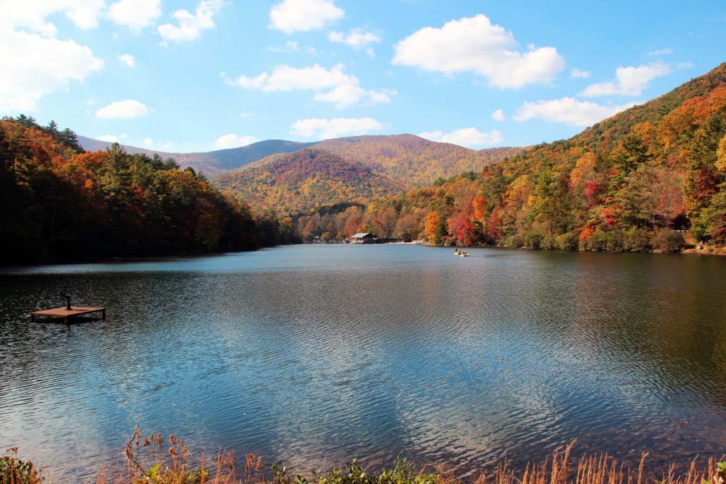 A stunning view of Lake Trahlyta, nestled amongst colorful fall foliage in Vogel State Park, one of the best family activities in North Georgia Mountains.