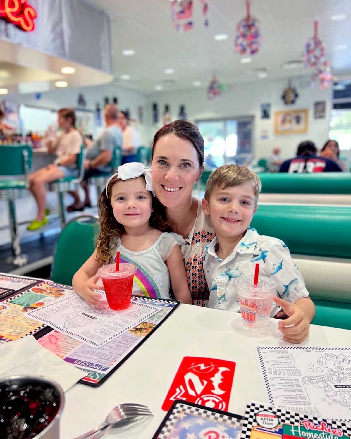 A mom and her two kids sit together at a restaurant. 