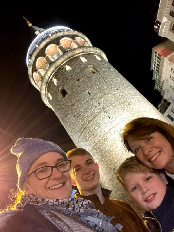 Four people pose in front of the Galata Tower in Istanbul.
