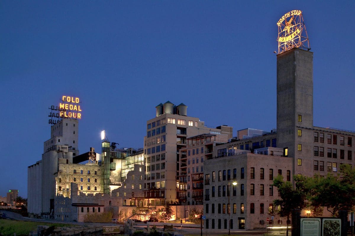 The exterior of Mill City Museum and the surrounding buildings lit up at night.