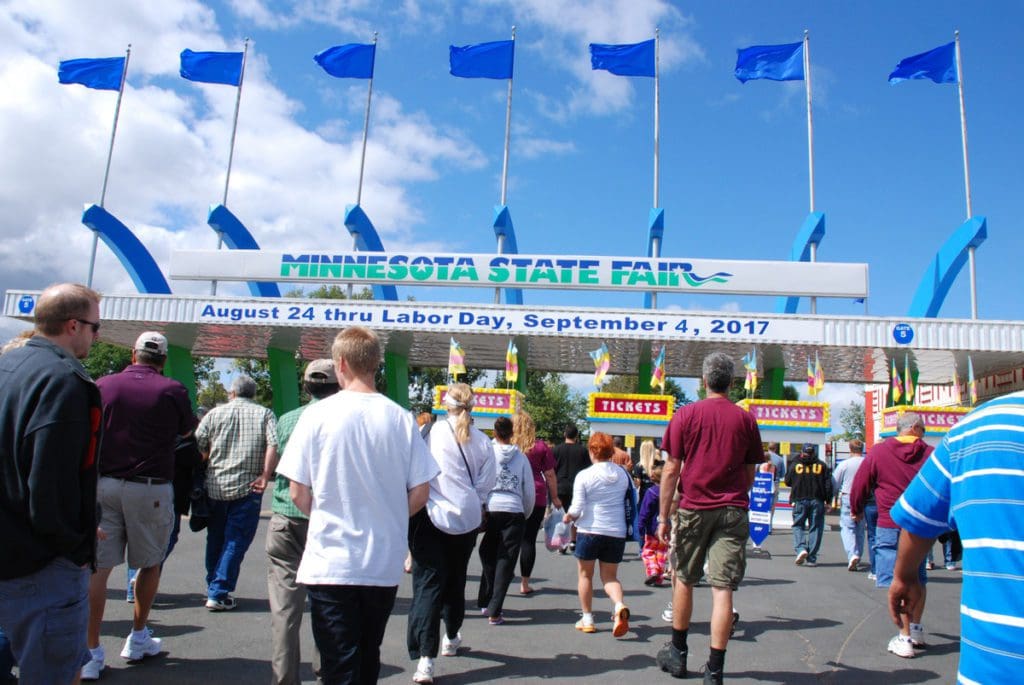 A crowd of people enters the gates of the Minnesota State Fair.