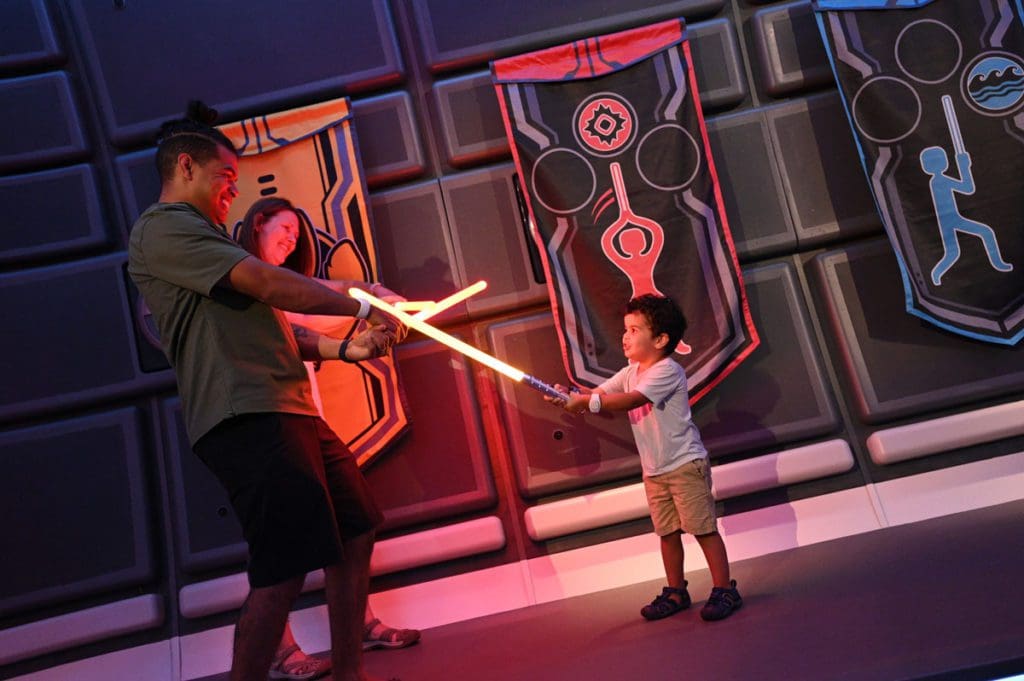Two parents and their toddler son "battle" with light sabers.