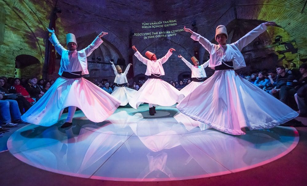 Five whirling dervishes dance during a show in Istanbul, a top experience on a Turkey itinerary for families.