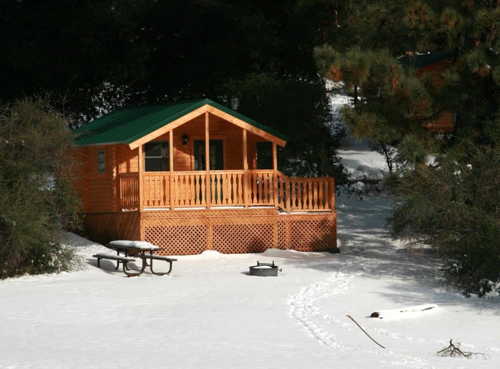 A cabin rests in a shaded area in the snow during winter in Julian.