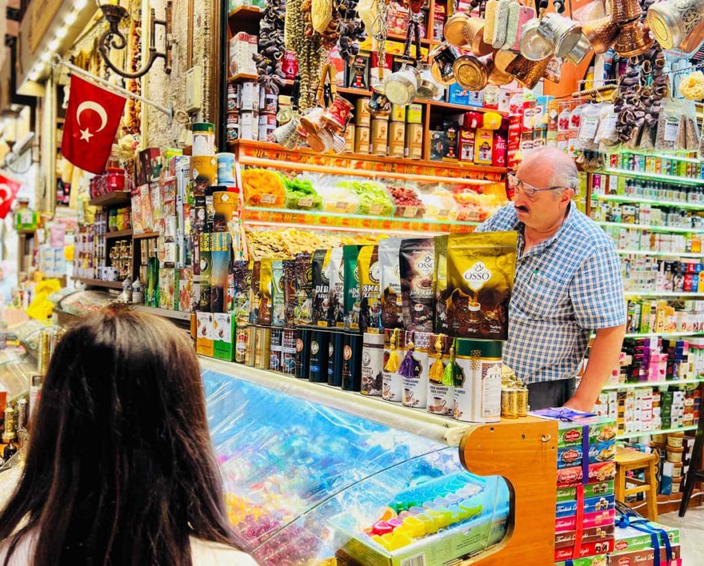 A young girl looks at a spice stall in Instanbul's Spice Market, while a shop keeper explains his wares.