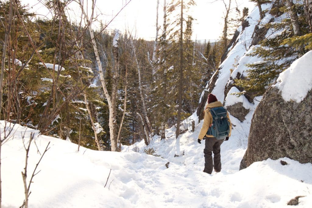 A woman hikes along a snowy path during the winter at Tettegouche State Park, one of the best places to visit in northern Minnesota with kids.