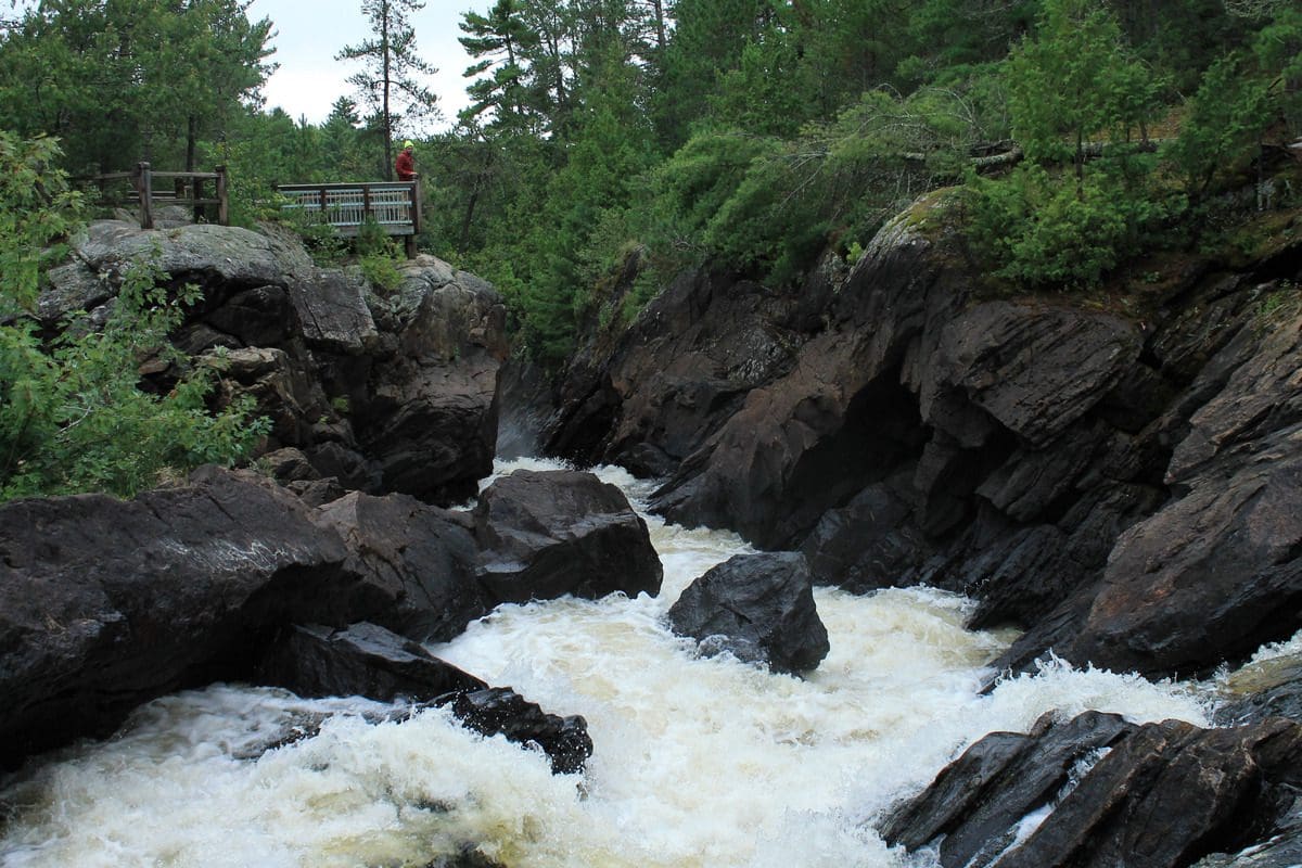 A river rushes over rocks near a hiking path in Voyageurs National Park.