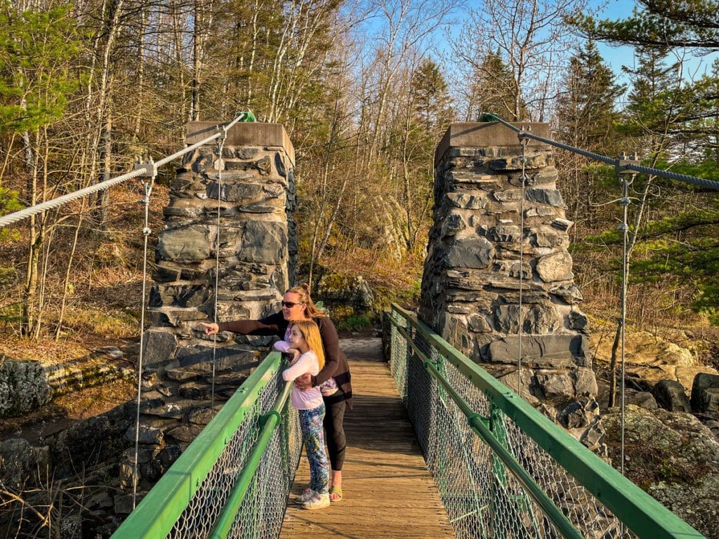 A mom points out onto a view of the river below, with her daughter standing next to her, at Jay Cooke State Park.