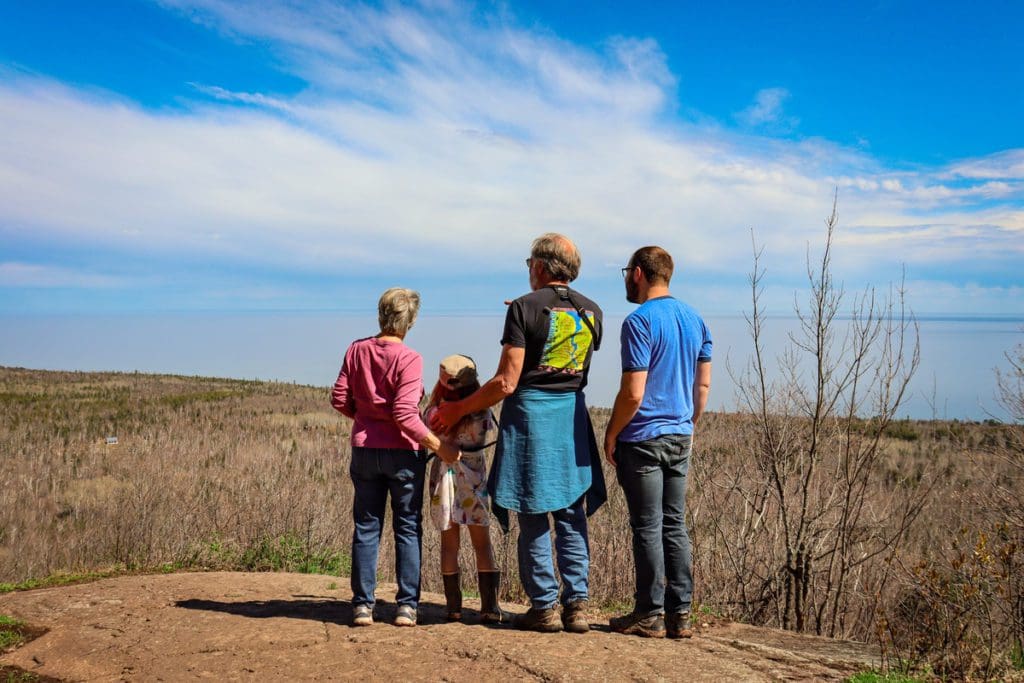 Four people, including grandparents, dad, and a young girl, look out onto a view of Minnesota in the spring atop Oberg Mountain, one of the best places to visit in northern Minnesota with kids.