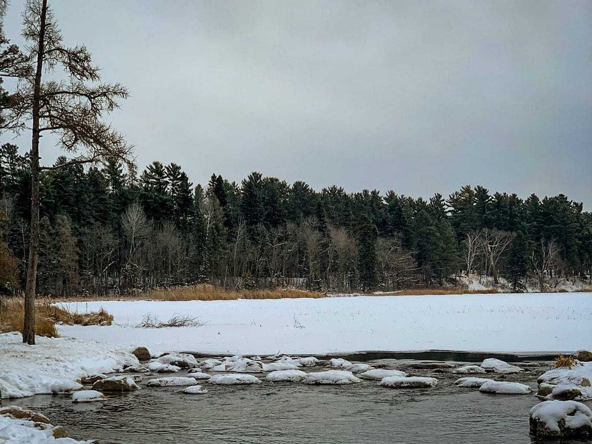 A view of the headwaters of the Mississippi River during winter, with an icy lake in the distance, at Itasca State Park.