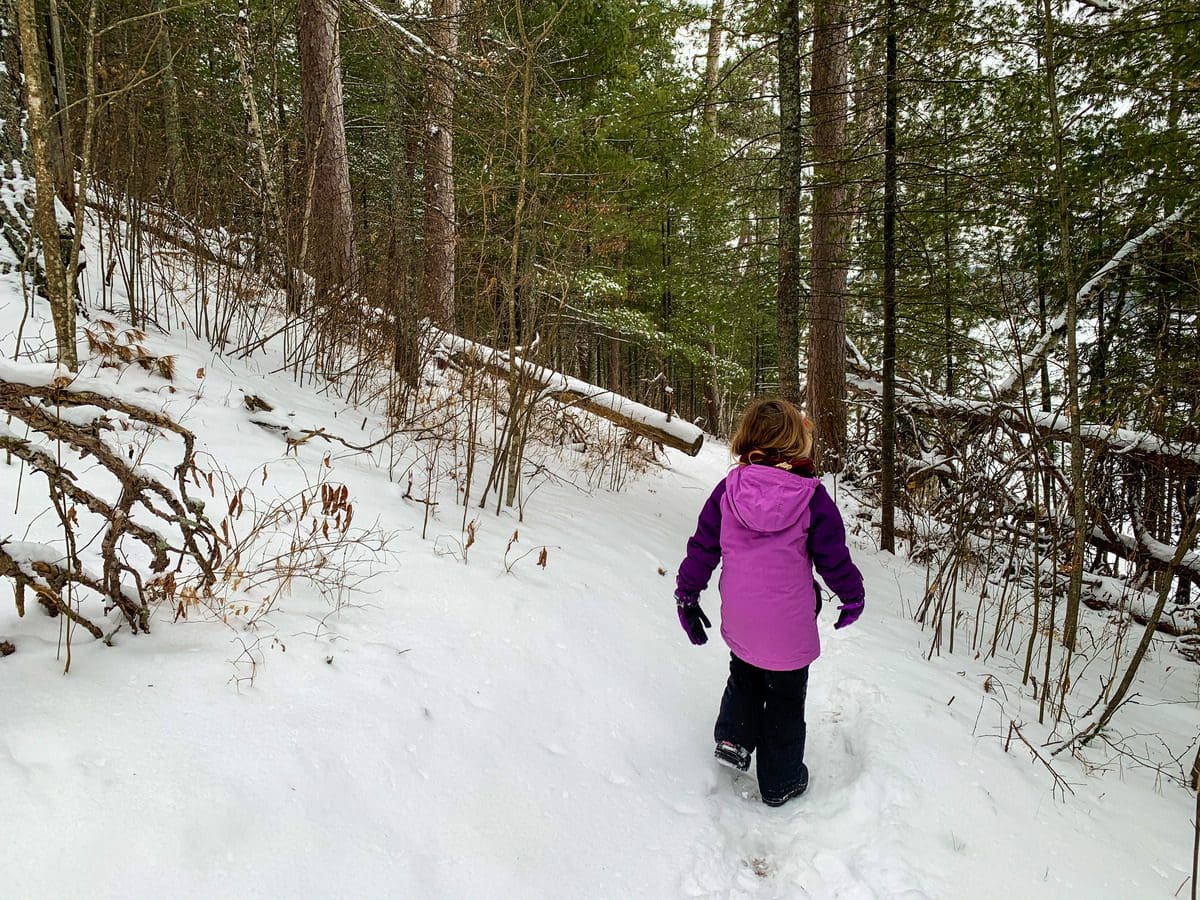 A young girl in winter gear marches along a snowy path during the winter at Itasca State Park.