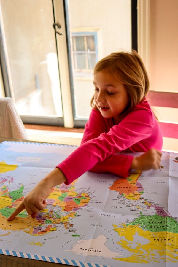 A young girl excitedly points to Europe on a map.