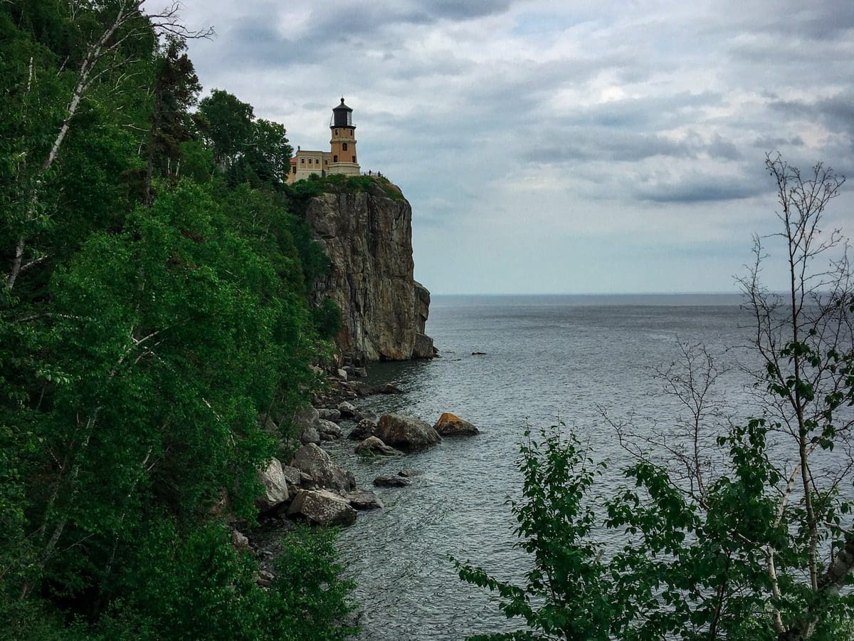A view of Split Rock Lighthouse through the trees on an overcast day.