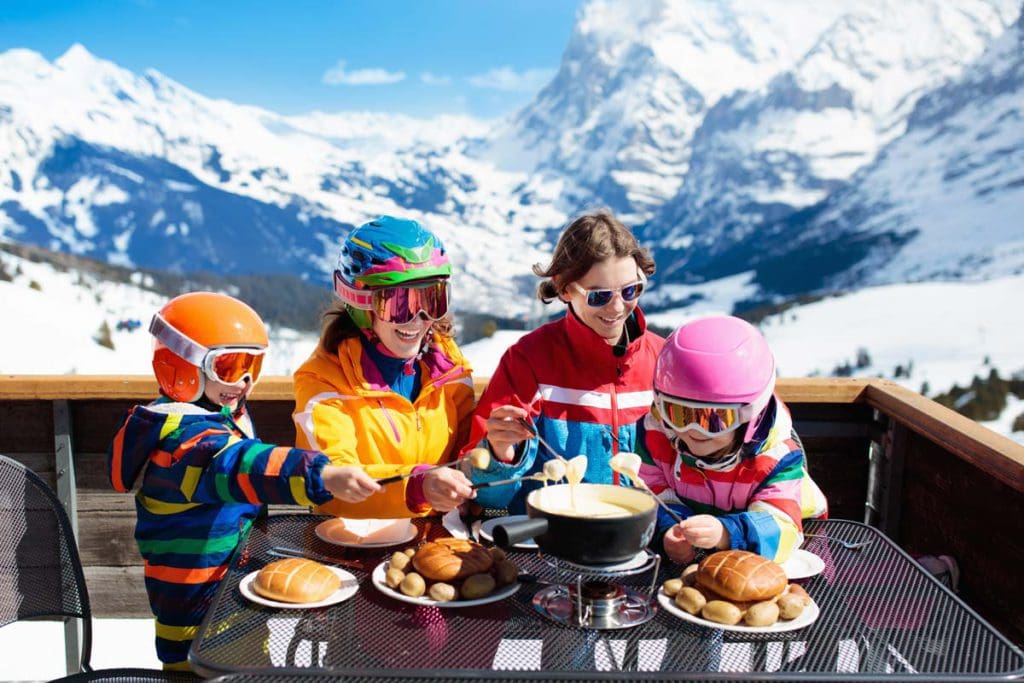 A family of four enjoys an apres-ski lunch in the mountains.