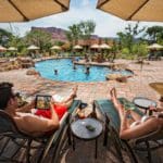 Parents enjoy a cocktail on poolside loungers, while watching their kids play in the outdoor pool at Gateway Canyons Resort & Spa.
