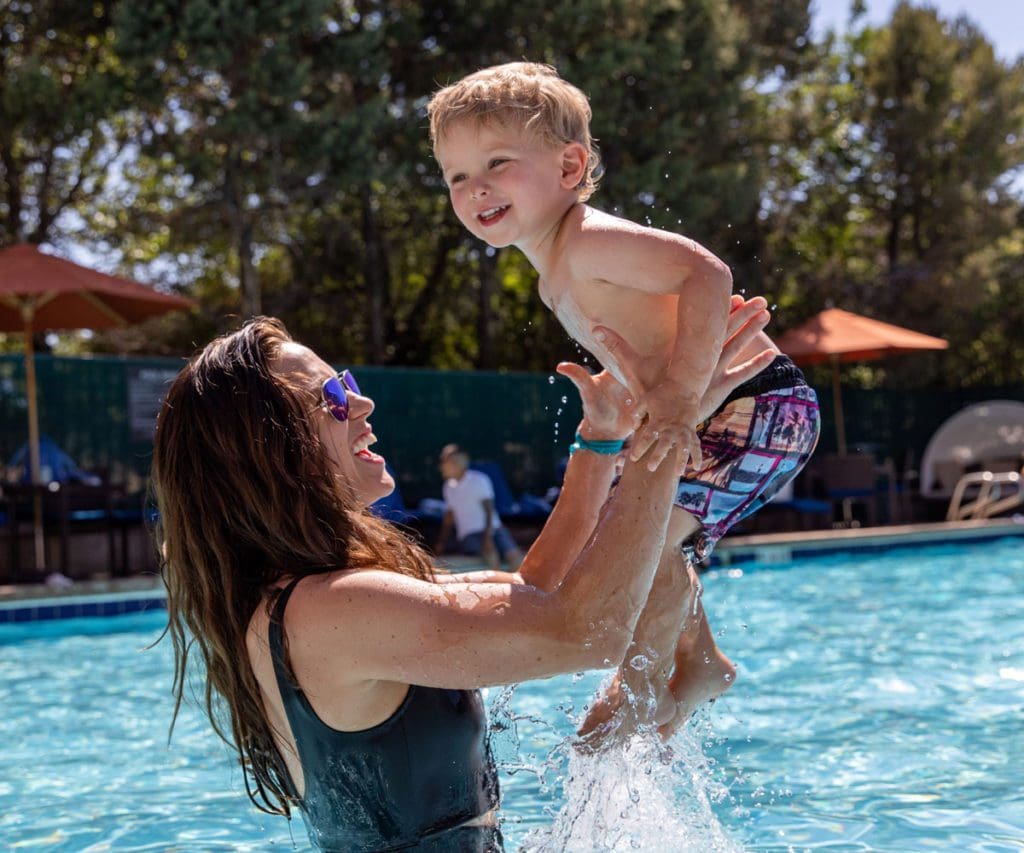 A mom throws her son in the area, while playing in a pool together at Hilton Denver Inverness, one of the best Denver hotels for families.
