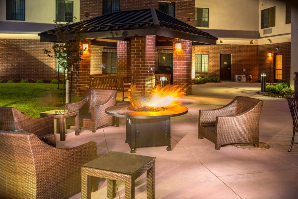 The outdoor courtyard with fire pit, featuring a cozy fire within, at Staybridge Suites Denver – Central Park, an IHG hotel at night.