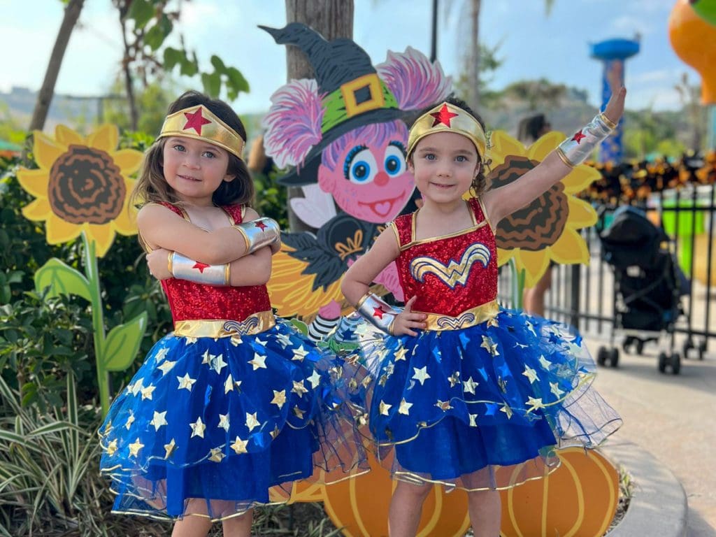 Two girls dressed in Wonder Woman costumes pose together at the Sesame Place San Diego Halloween event.