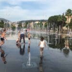Several kids play in a splash zone in Nice.