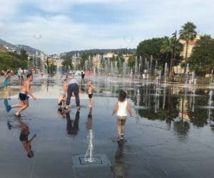 Several kids play in a splash zone in Nice.