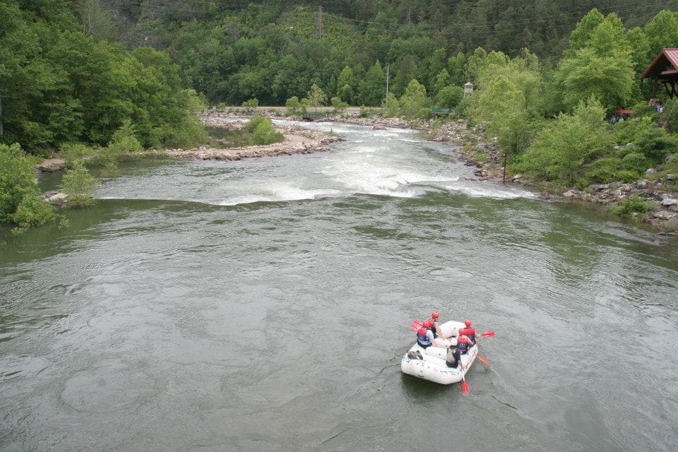 A raft carrying six people makes its way down a river, one of the best family activities in North Georgia Mountains.