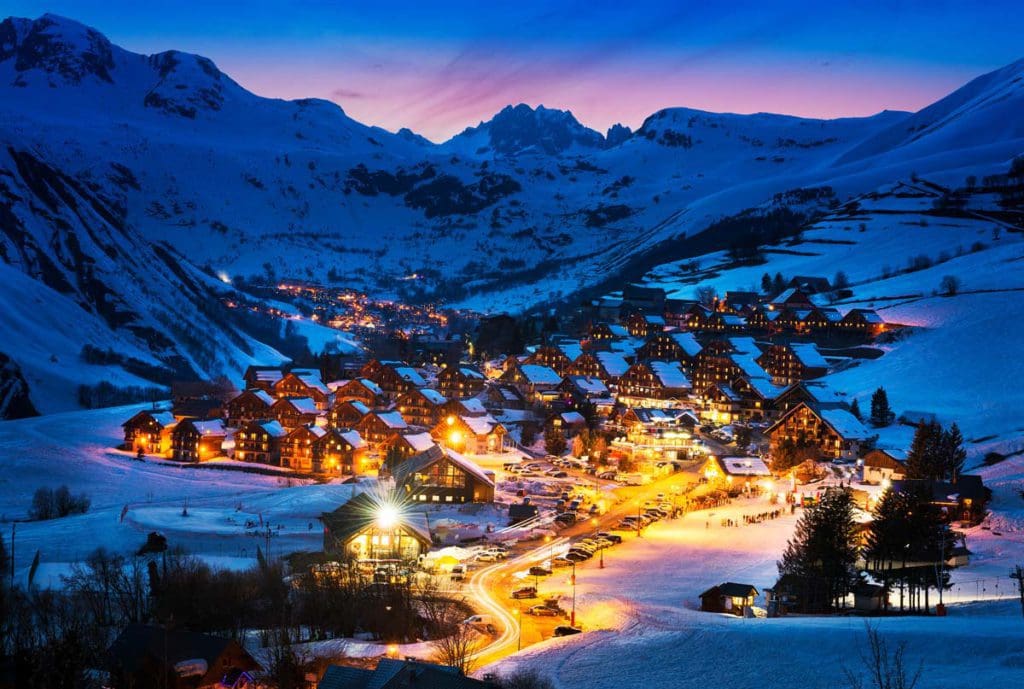 An aerial view of Saint Jean d'Arves, a town nestled in the French Alps, lit up at night, one of the best places to ski Europe with Kids.
