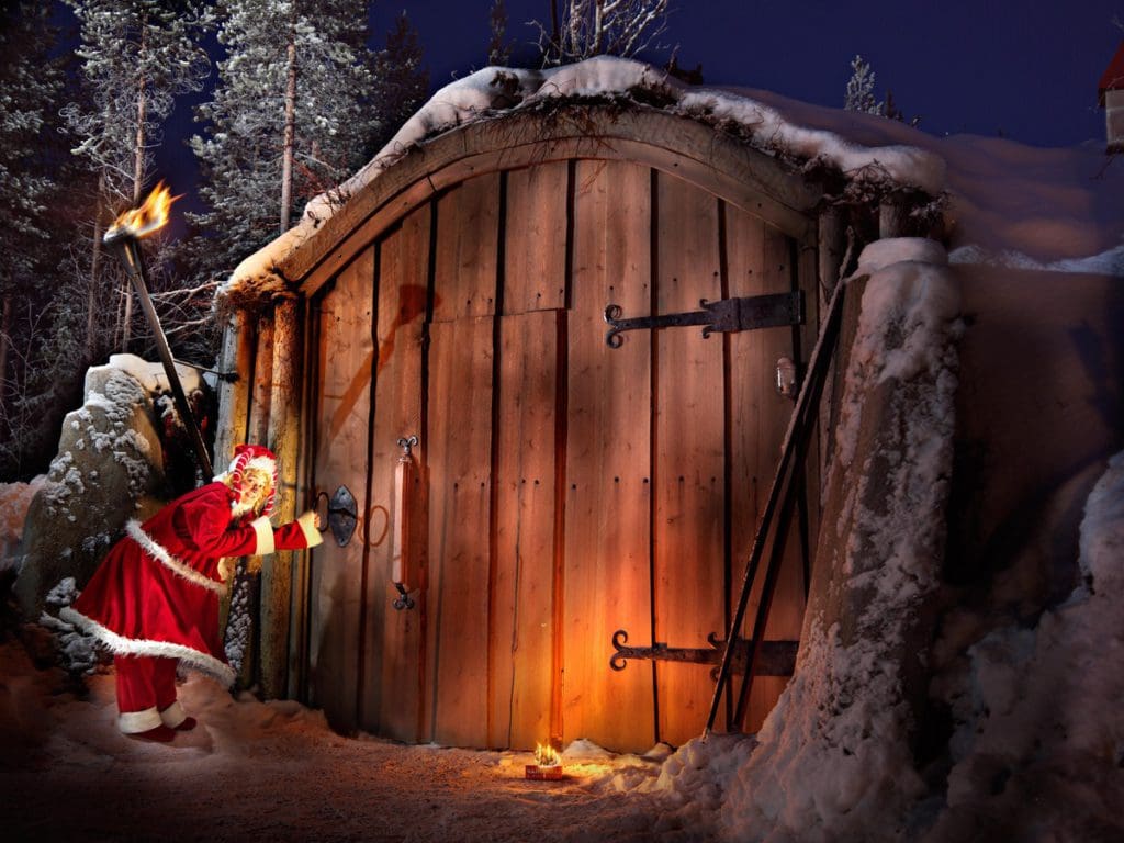 Santa knocks on a large door in the Santa Claus Secret Forest in Joulukka, Finland.