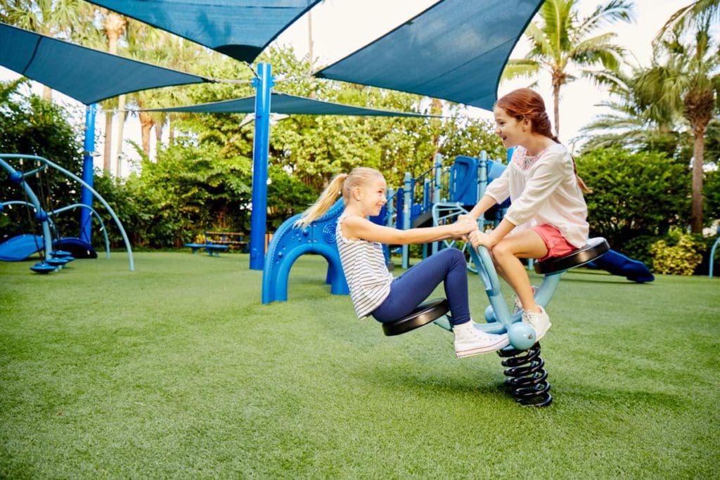 Two kids play on playground equipment together at The Breakers.