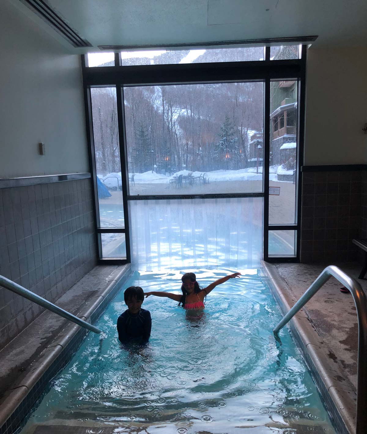 Two kids swim in a cozy hotel pool while enjoying winter in Stowe.